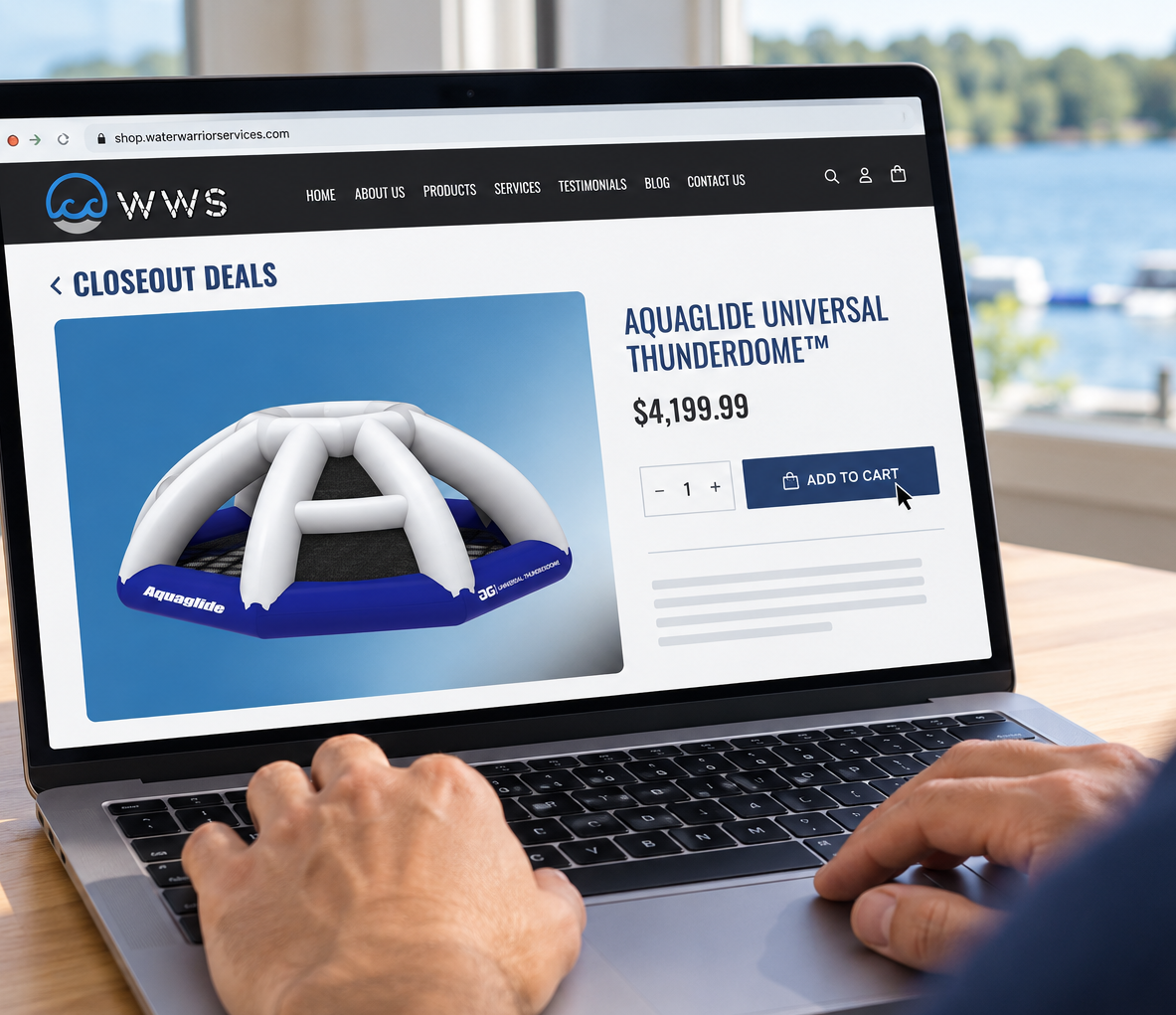 A person using a laptop at a table, with the screen showing a WWS website page for the Aquaglide Universal ThunderDome inflatable pool float. A real outdoor waterfront environment is visible in the background.
